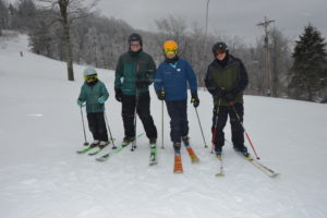 Photo of four skiiers with snowy background