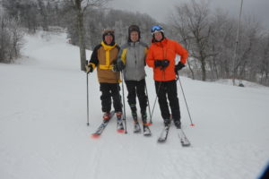 Photo of three skiiers with a snowy background