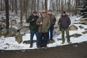 Photo of four clays shooters with snow and trees in background