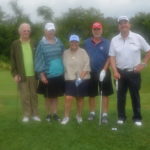 Photo of 5 people standing next to each other on a golf green