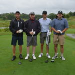 Photo of 4 men standing next to each other on a golf green